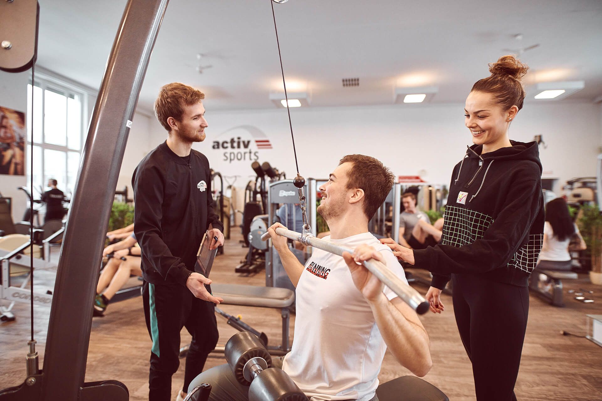 Frau mit Trainer am Latzug im Fitness Unlimited Fitnessstudio in Berlin Charlottenburg